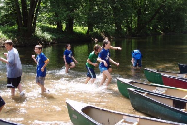 Kids playing by canoes in River Quest Field School